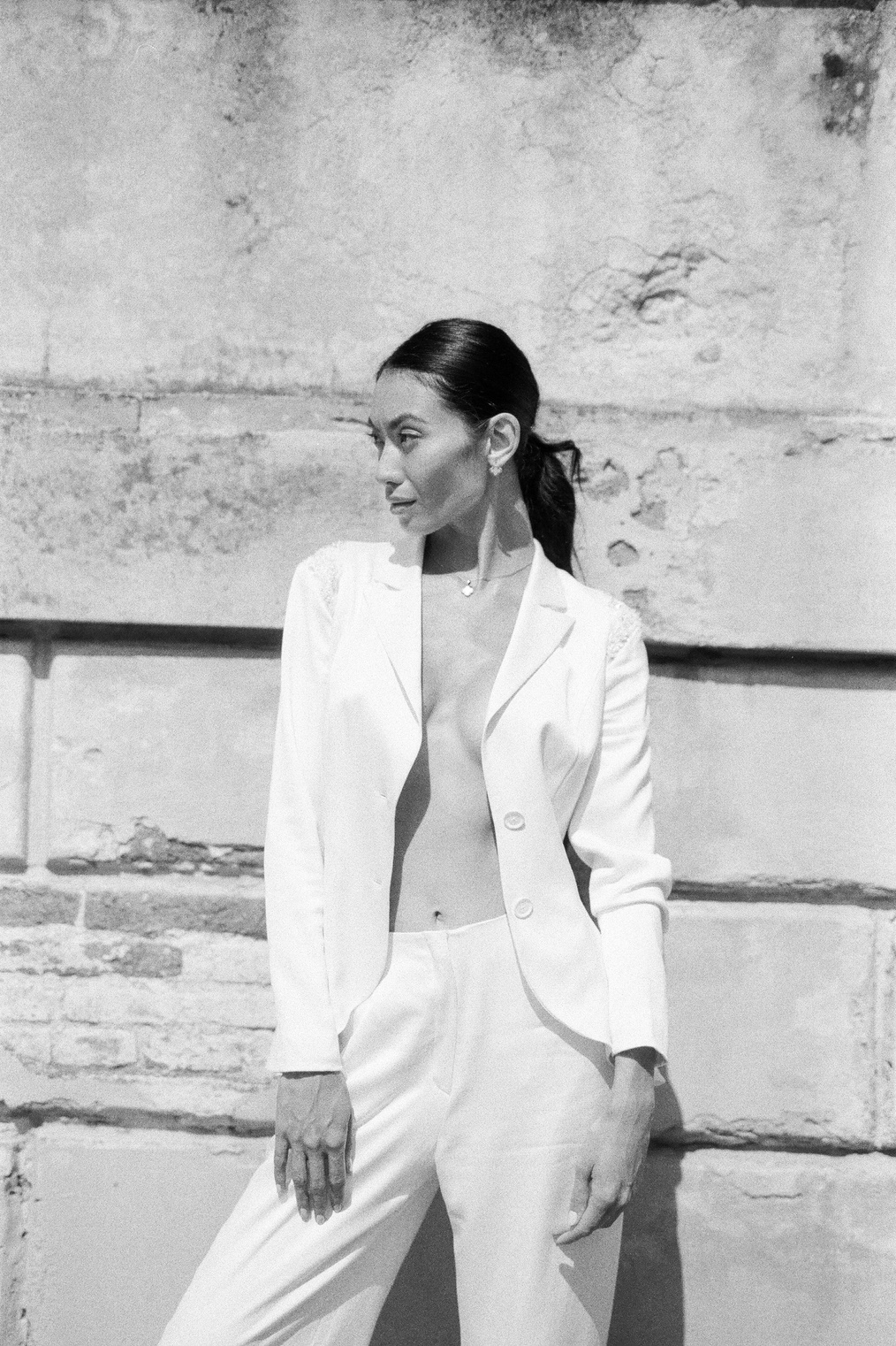 a woman in a white suit posing against a wall